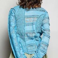 Teal blue lace long-sleeve top with exposed seams and round neckline, back view
