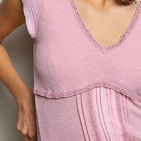 Soft pink textured knit top close-up with lace-trim V-neck and short sleeves