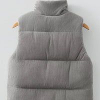 Gray corduroy puffer vest with stand collar; quilted, padded back panel with horizontal baffles.