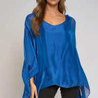 Royal blue silk blouse with round neck and batwing sleeves, flowing drape.