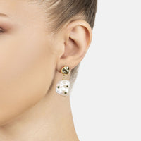 Gold drop earrings with white baroque pearls and green inset accents on ear