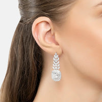 Silver-tone drop earrings with marquise clusters and round charm, close-up on ear