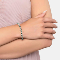 Silver tennis bracelet with emerald-green stones on inner wrist