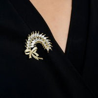 Gold laurel leaf ribbon brooch with crystal-like stones on black fabric