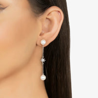 Pearl drop earrings dangling from ear with star charm and silver chain