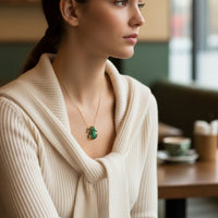 Gold frog pendant necklace on model with green gem-like detail