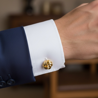 Gold-tone knot cufflink on a white shirt cuff with coiled knot clasp