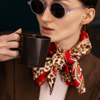 Woman wearing round sunglasses with dark lenses and light blue frames