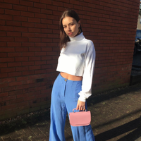 Pastel pink leather flap bag with short top handles, held in hand