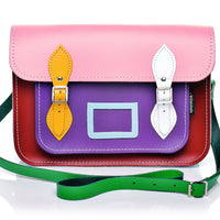 Pink leather satchel with flap, multicolor panels, yellow/white buckles, green strap