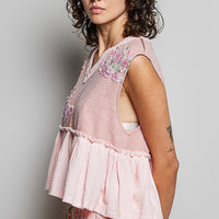 Powder pink sleeveless top with V-neck, floral shoulder patch and gathered peplum