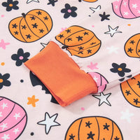 Close-up: dusty pink pumpkin-print fabric with orange-trim collar detail