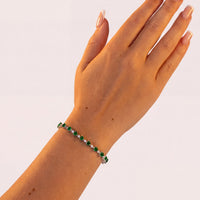 Green heart tennis bracelet on wrist, silver chain with small link design