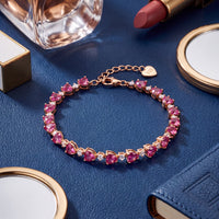 Gold-tone bracelet with heart-shaped pink stones and small round clasp tag