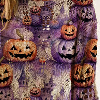 Plus size loose knit cover-up close-up with purple fabric and orange jack-o'-lantern pumpkin graphics.
