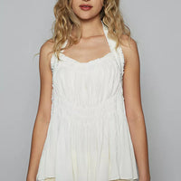 Off-white halter top with shirred bodice, smocking detail, and scalloped edging