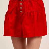 Red denim shorts with pintucked elastic waist, button placket, and waist tie detail.