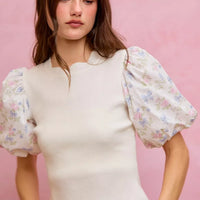 White knit sweater top with floral puff sleeves and scalloped hem at the waist