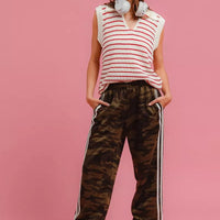 Camouflage track pants with long white side stripe and jogger-style tapered silhouette.