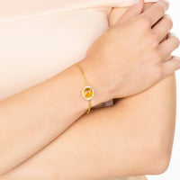 Gold citrine gemstone bracelet on wrist with oval center and crystal halo