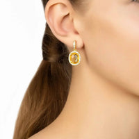 Gold citrine oval drop earrings with crystal halo, shown on ear