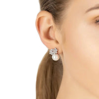 Silver flower stud earrings with pearl drops, worn on ear
