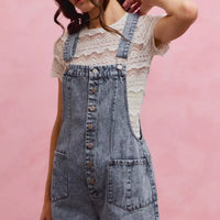 Light wash denim overall romper with adjustable straps and front buttons, front slant pockets