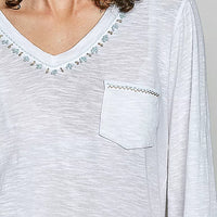 Off white V-neck knit top detail with contrast hand-stitched trim and chest pocket.