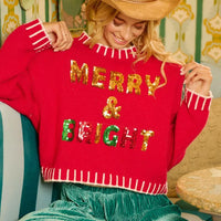 Red Christmas sweater with gold “MERRY & BRIGHT” sequin text and white fringe hem