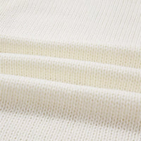 Close-up of off-white knit cardigan hem ribbing and textured sweater knit.