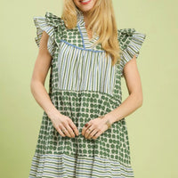 Green patchwork tiered mini dress with flutter sleeves, striped bodice, and circular dot print.