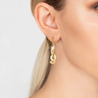 Gold serpent hoop earring with sparkling stones, shown on an ear close-up