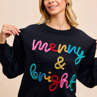 Black crewneck sweater featuring multicolor tinsel "Merry & bright" lettering.