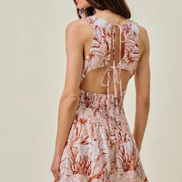 Back view of lined mini dress with smocked bodice and coral-brown shell print, tie straps