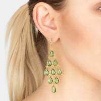 Gold peridot chandelier drop earrings with teardrop green stones, worn on ear
