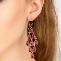 Rose gold cascade earrings with pink teardrop gems hanging below the ear