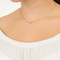 Gold evil-eye pendant necklace on model, small round blue opalite charm