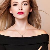 Gold evil eye necklace worn with off-shoulder top, small blue eye pendant
