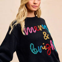 Black sweater with multicolor tinsel "Merry & bright" lettering across the chest.