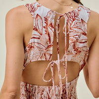 Back view of coral and white shell-print mini dress with smocked waist and tied open-back