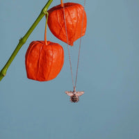 Gold-tone honey bee pendant necklace hanging from a thin chain