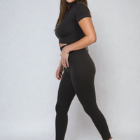 Black ribbed half-zip crop top and high-waist leggings set, fitted two-piece.