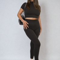Black ribbed half-zip crop top and high-waist leggings set, fitted two-piece.