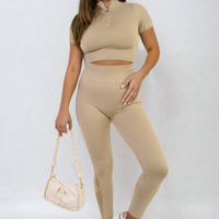 Beige ribbed half-zip crop top and high-waist leggings set, holding white bag