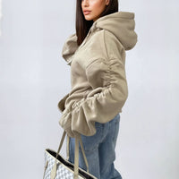 Oversized beige hoodie with ruched sleeves, front pouch pocket, and drawstring hood