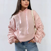 Light pink oversized hoodie with drawstring hood, front pouch pocket, and ruched sleeves