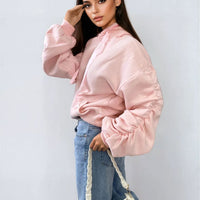 Oversized pink hoodie with ruched sleeves, pouch pocket, and drawstring hood