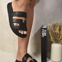 Black slide sandals with wide straps and geometric cutout panels