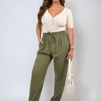 Olive-green high-waist drawstring trousers with side pockets and gathered waistband.