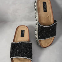 Black glitter platform slide sandals with white braided trim and tan insole